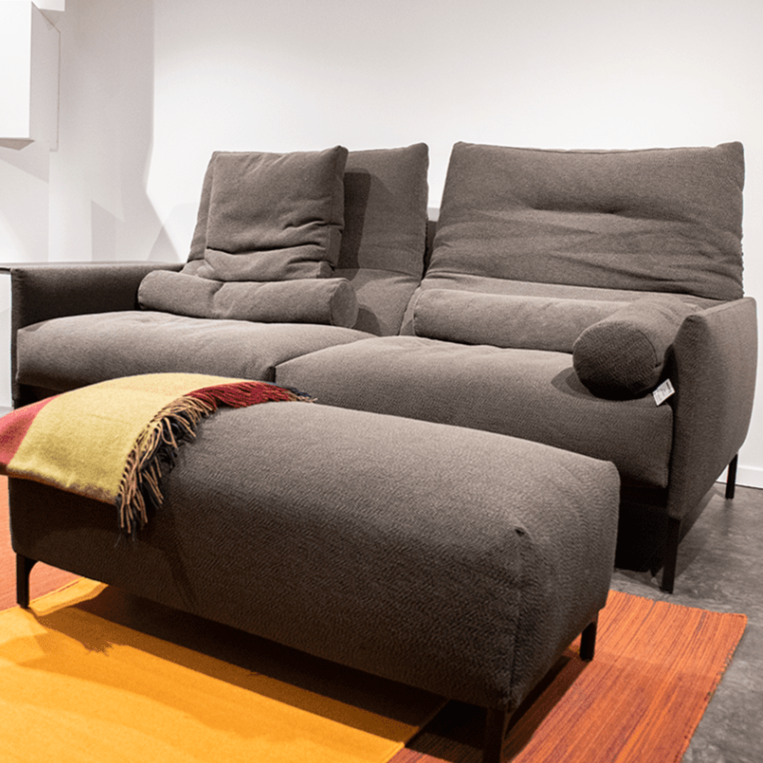 COR graues Sofa und Hocker, leicht seitlich von vorne